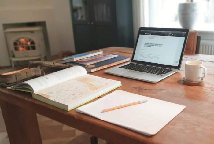Laptop with textbooks and coffee on study desk