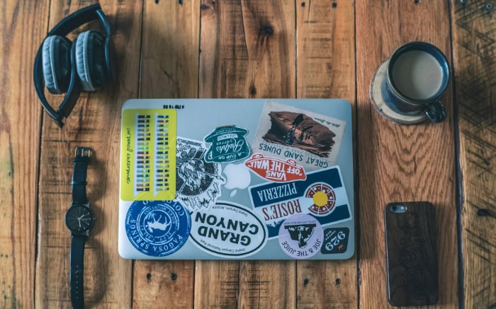 Laptop with travel themed stickers on wooden desk