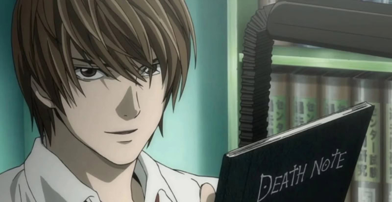 Light Yagami holding a Death Note notebook smiling