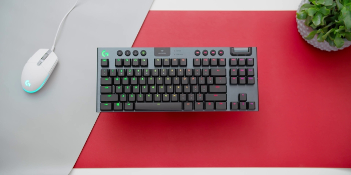 Gray Logitech G915 TKL near white mouse on red surface