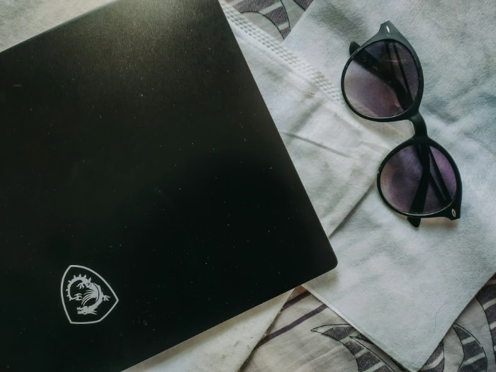 MSI laptop with dragon logo next to sunglasses on fabric