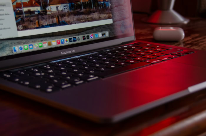 MacBook Pro keyboard and dock on red surface