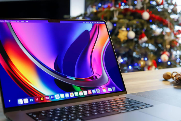 MacBook Pro with colorful display near Christmas tree