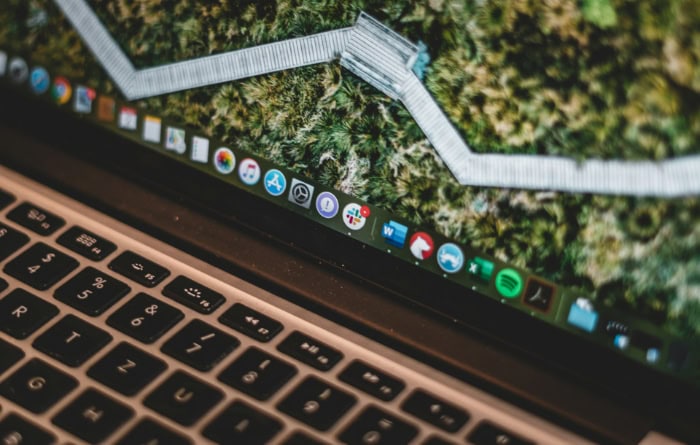 MacBook laptop displaying nature wallpaper and app icons