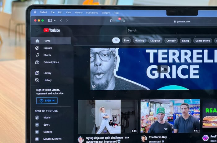 MacBook screen showing YouTube homepage in dark mode