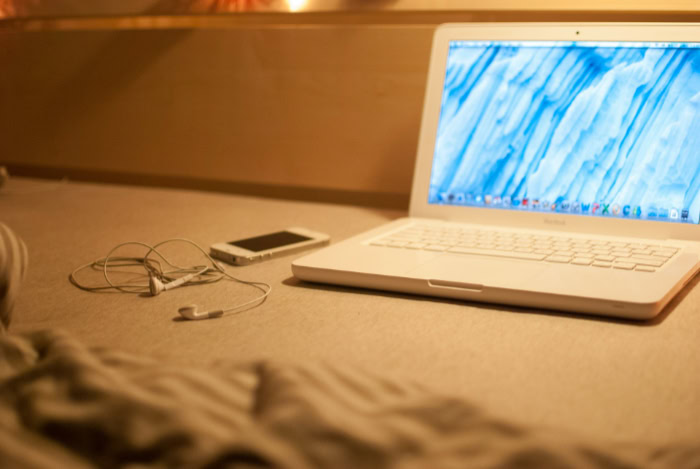 MacBook with earbuds on wooden desk surface