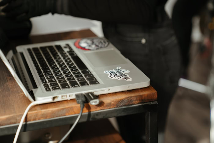 MacBook with stickers plugged in on wooden desk