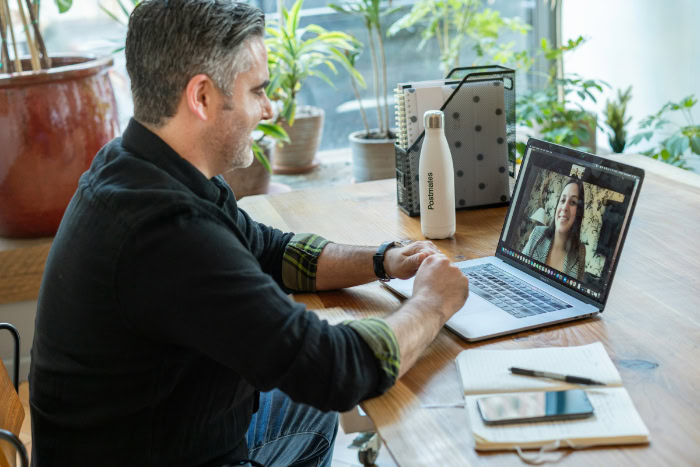 Man at a desk engaged in a video call on a laptop