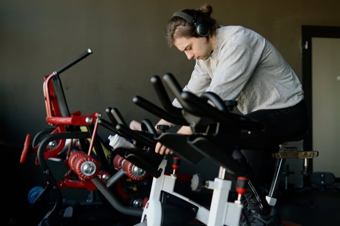 Man cycling indoors wearing wireless headphones