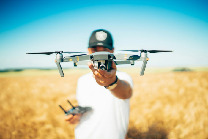 Man holding DJI Mavic Pro drone in wheat field