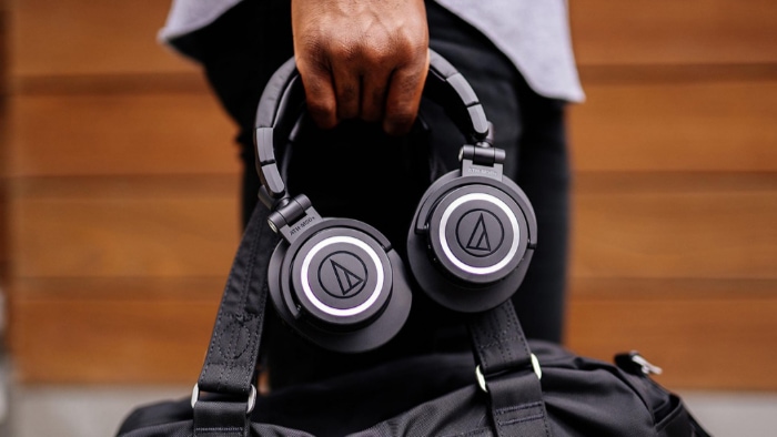 Man holding black Audio Technica headphone