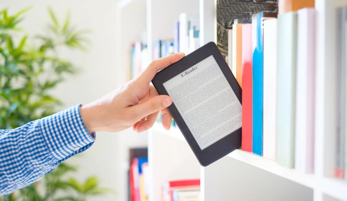 Man holding black ereader on bookshelf