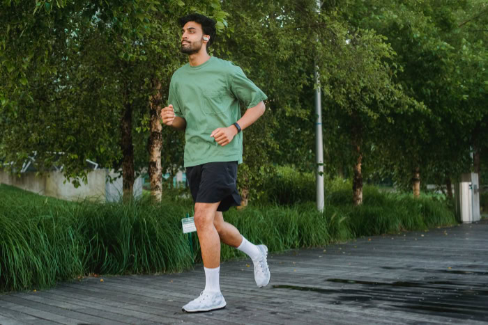 Man jogging on a wooden path surrounded by greenery