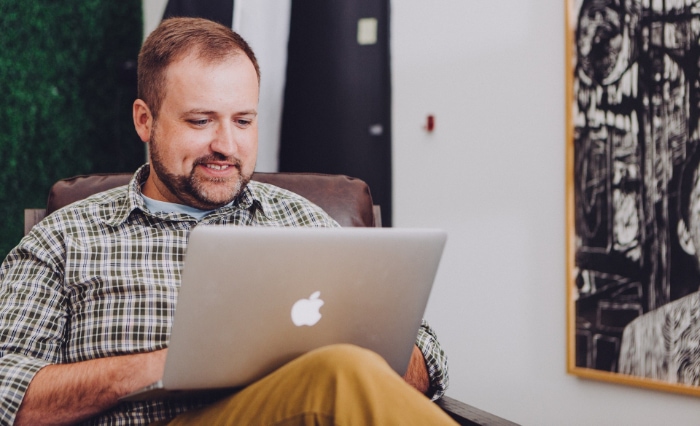 Man smiling and using macbook