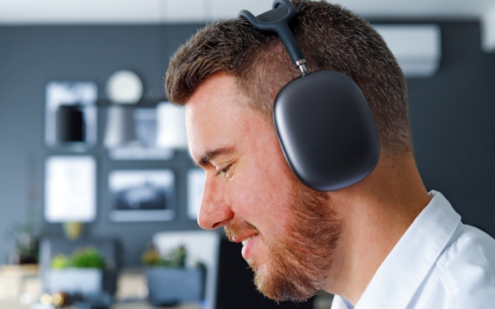 Man smiling while wearing wireless over ear headphones in an office setting