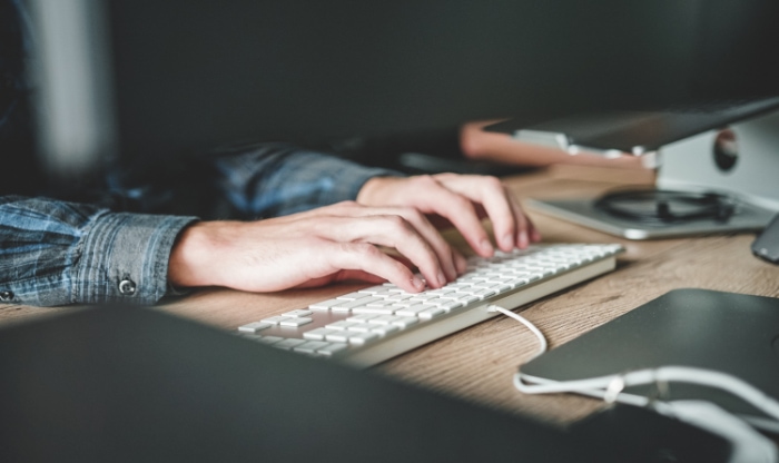 Man typing on white keyboard on desk