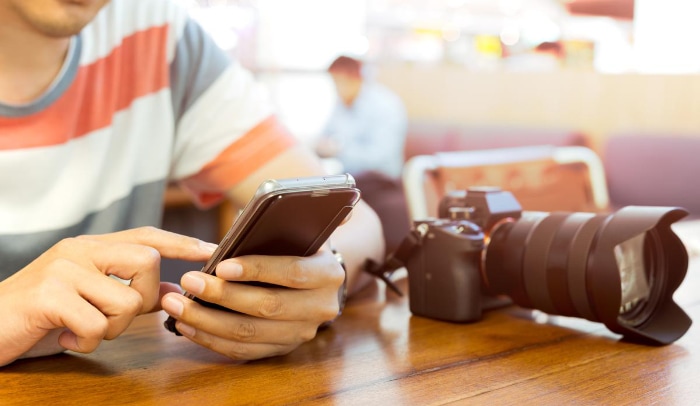 Man using smartphone near DLSR camera