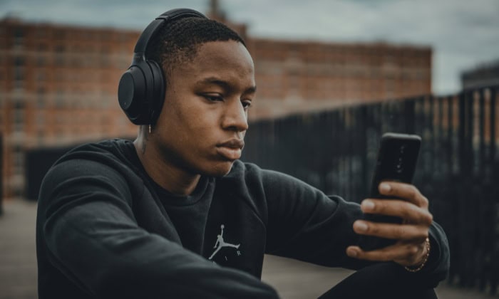 Man wearing headphones while looking at his phone