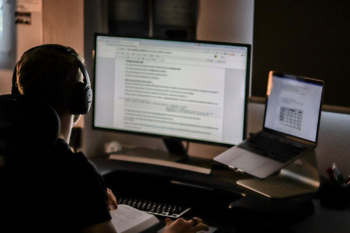 Man with headphones coding at computer in dark