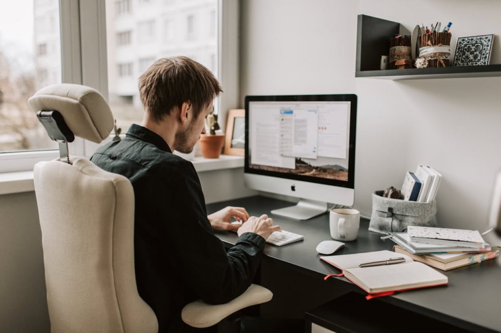 Man working on iMac computer in home office setting