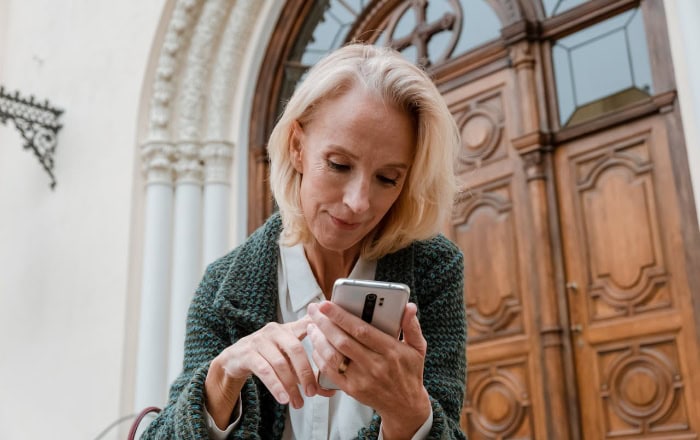 Mature woman using smartphone outside ornate building