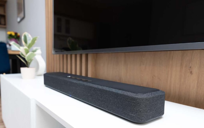Minimalist soundbar on white cabinet against wooden background