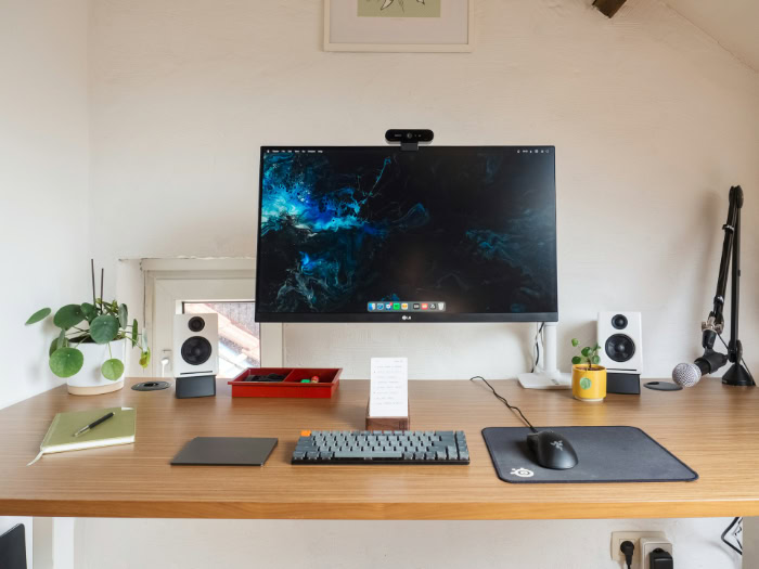 Minimalist wooden desk setup with monitor and speakers