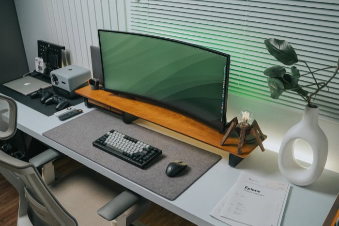 Minimalist workspace with curved ultrawide monitor on wooden stand