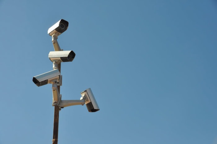 Multiple surveillance cameras mounted on pole against blue sky