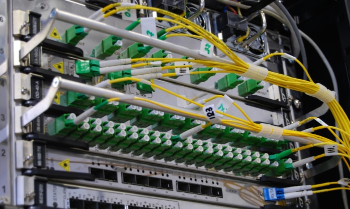 Network server room with yellow fiber optic cables connected to green ports