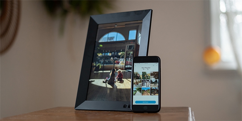 Black Nixplay Smart Digital Picture Frame beside black smartphone