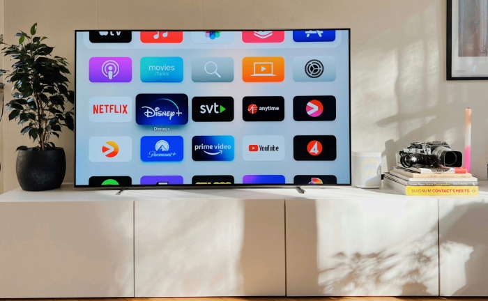 OLED TV displaying colorful app icons in a bright living room