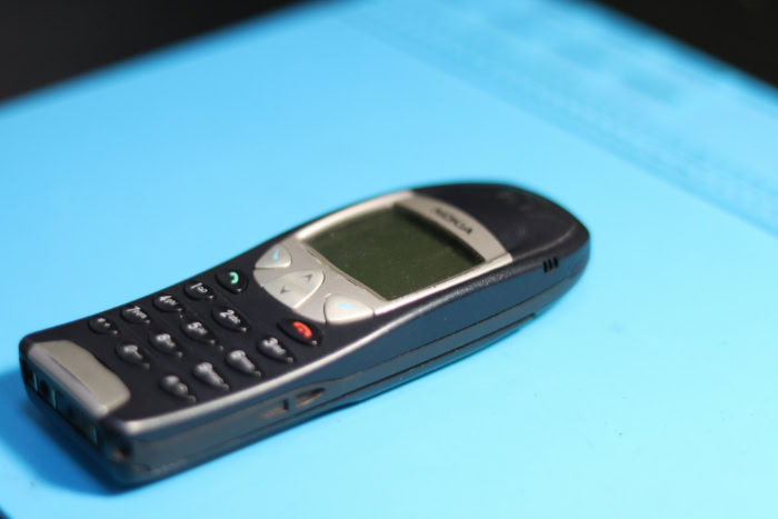 Old Nokia burner phone on blue surface