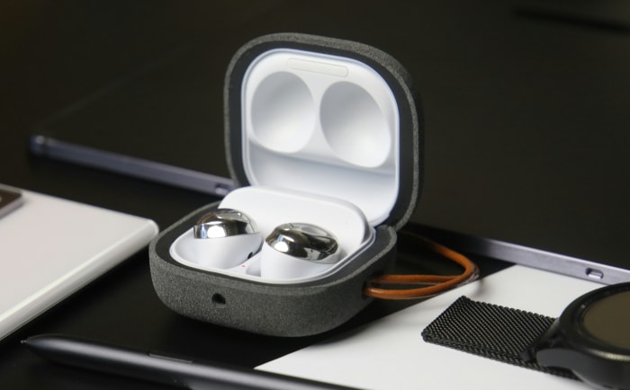 Open case of earbuds on a desk with tech accessories