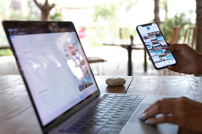 Open laptop and smartphone on a wooden table outdoors