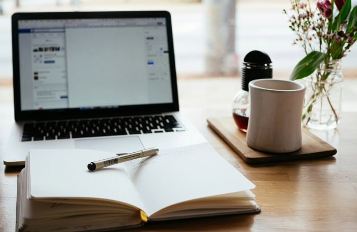 Open laptop notebook and coffee mug on a wooden desk