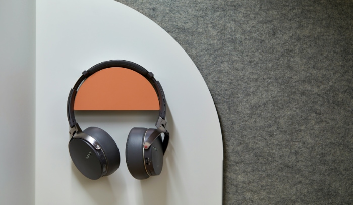 Over ear headphones resting on a white and orange half circle shelf