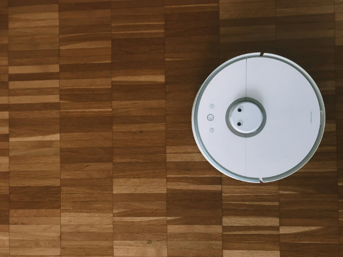 Overhead shot of white robot vacuum on wood floor