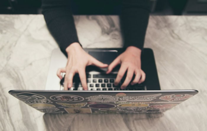 Overhead view of hands typing on laptop with stickers