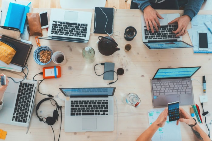 Overhead view of workspace with multiple laptops and devices