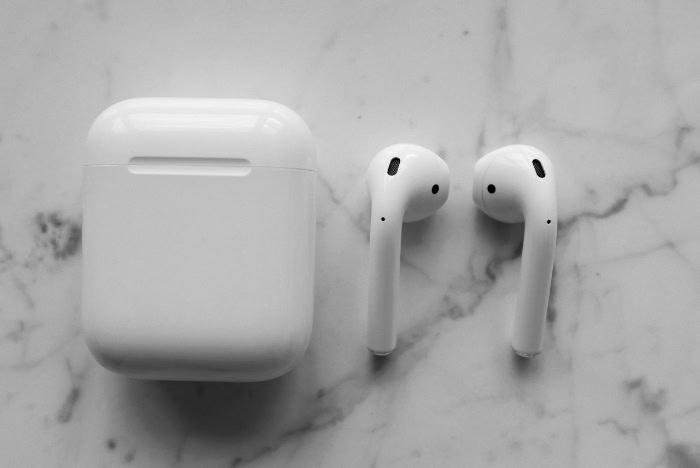 Pair of AirPods next to closed charging case