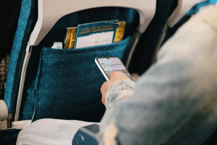 Passenger using a smartphone in an airplane seat