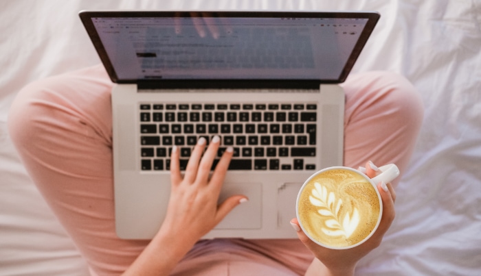 Person using laptop and holding cup of coffee