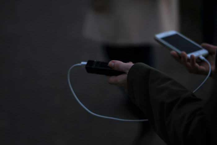 Person charging smartphone with portable power bank