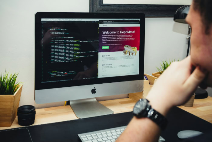 Person coding HTML and CSS on a desktop computer screen