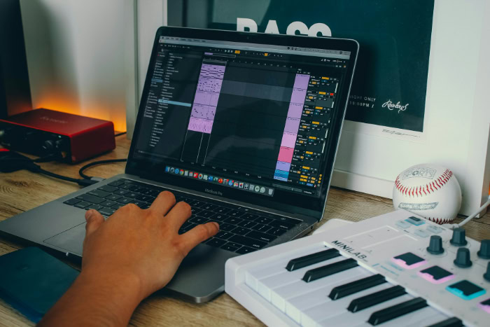 Person editing music on laptop with MIDI keyboard