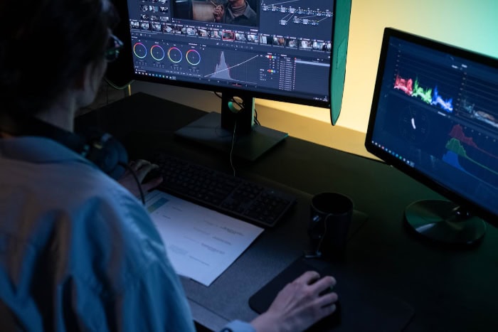 Person editing video with dual monitor setup