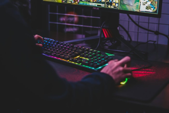 Person gaming on a desktop with RGB keyboard