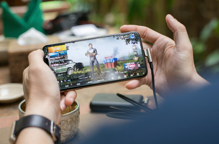 Person gaming on smartphone playing battle royale shooter outdoors