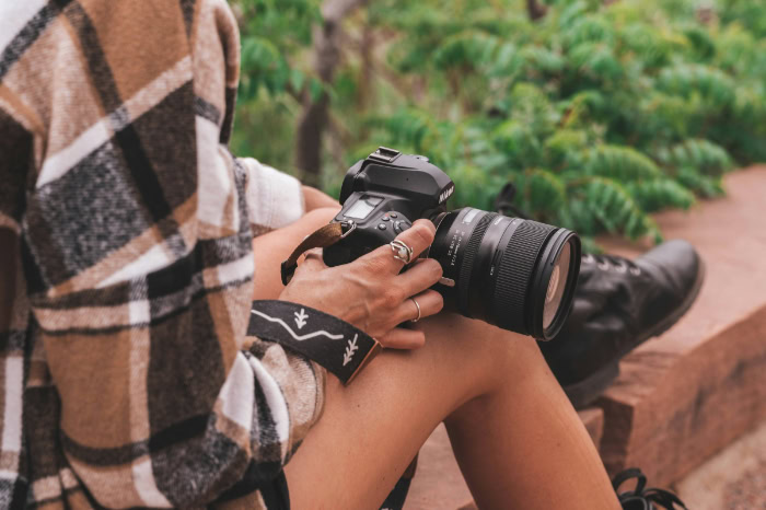 Person holding Nikon DSLR camera outdoors